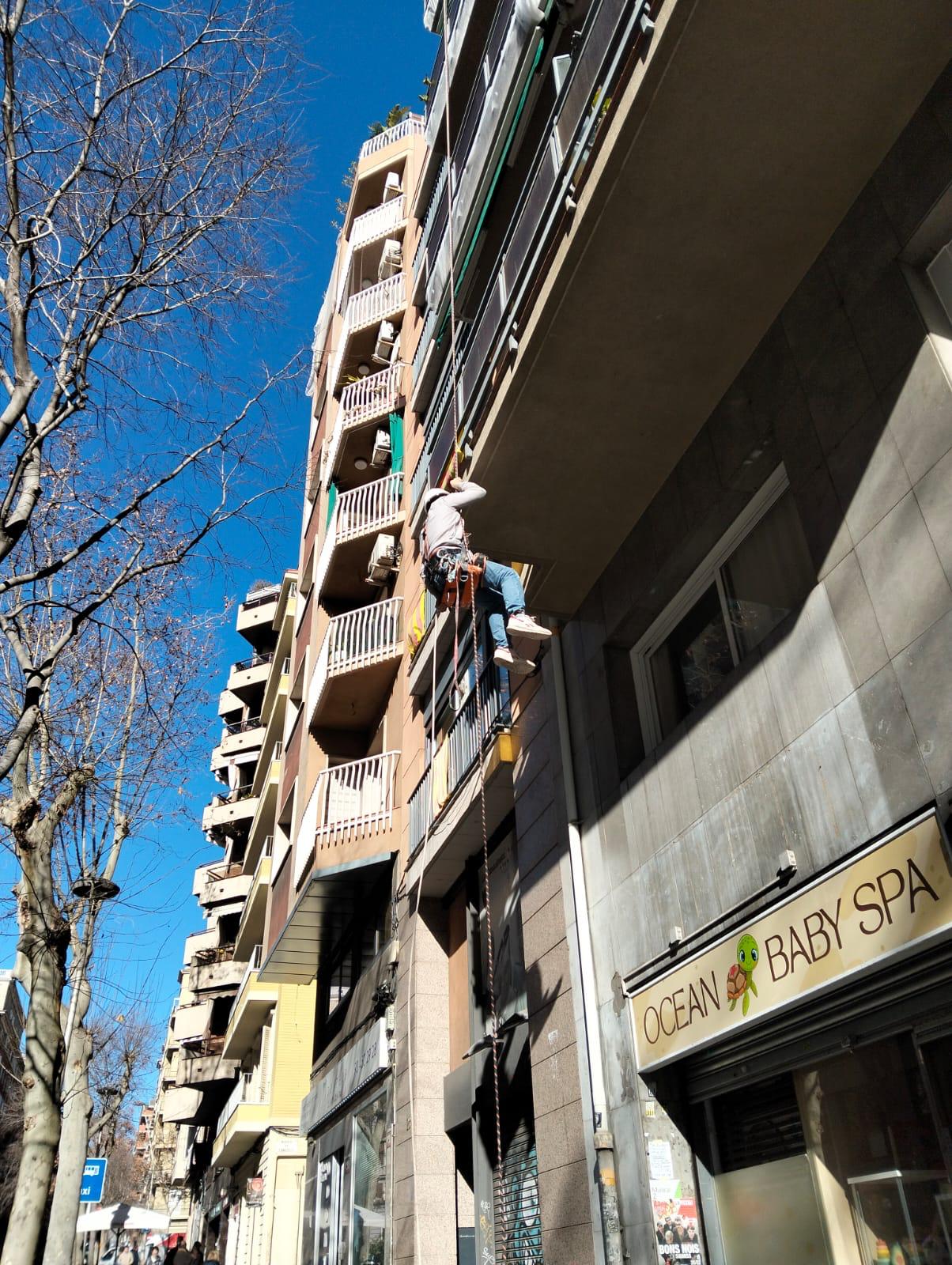 Técnico trabajando desde la cuerda en la fachada alta de un edificio